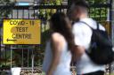 People pass a Covid-19 test centre sign at a walk-through testing centre. Picture: Andrew Milligan/ PA Wire/PA Images