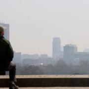 A man sitting on Primrose Hill looks at smog over London