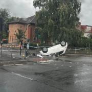 Police vans surround the overturned car in Rush Green